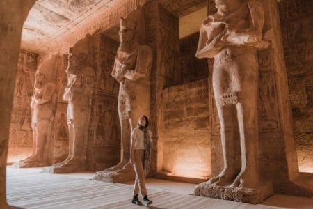 A Tourist Looking Up At The Colossal Statues Of Ramesses Ii Inside The Great Temple Of Abu Simbel During An 11 Day Egypt Unesco Heritage Tour Faiyum Nile Cruise