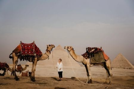 A Traveler Standing Between Two Camels With The Giza Pyramids In The Background During A 12 Day Cairo Alexandria Sharm El Sheikh Christmas Tour.