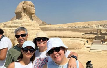 Smiling tourists taking a family photo in front of the Great Sphinx of Giza during a 12 day senior egypt tour