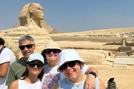Smiling tourists taking a family photo in front of the Great Sphinx of Giza during a 12 day senior egypt tour