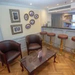 Elegant indoor bar with plush stools, hanging glassware, and a view of the Nile.