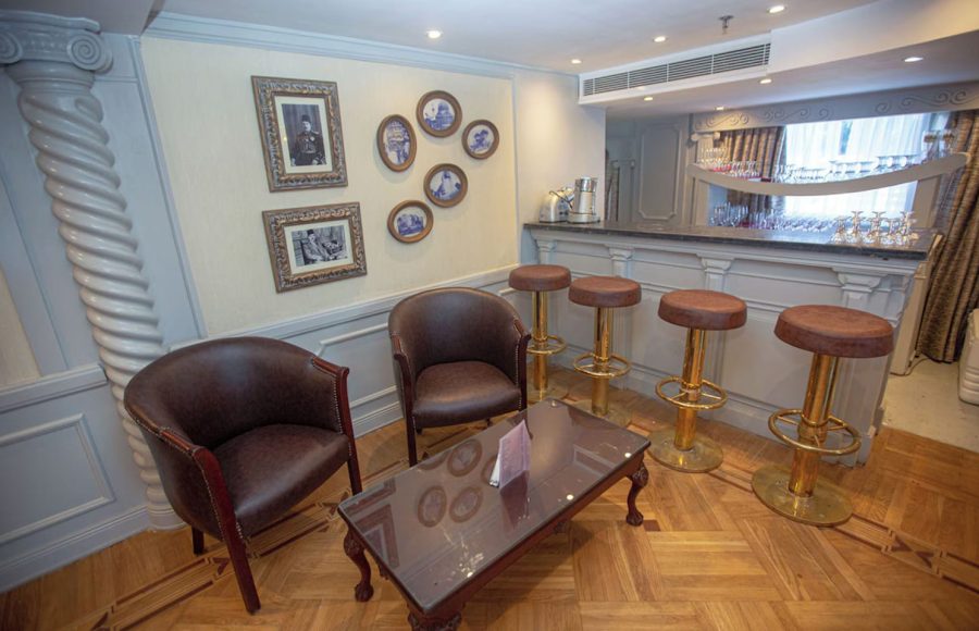 Elegant indoor bar with plush stools, hanging glassware, and a view of the Nile.