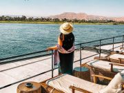 a woman standing on a deck of nile cruise Aswan to Luxor overlooking a body of water