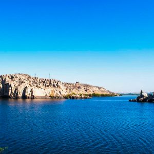 A stunning panoramic view of Lake Nasser, showcasing its serene blue waters against the vast desert backdrop and ancient ruins nearby.