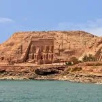 The Great Temple of Ramesses II at Abu Simbel, carved into the cliff face, viewed across the water of Lake Nasser, often visited on a tour from Aswan.