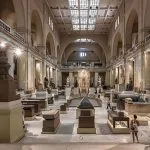 Large stone statues and sarcophagi displayed in the grand central hall of the Egyptian Museum in Cairo.