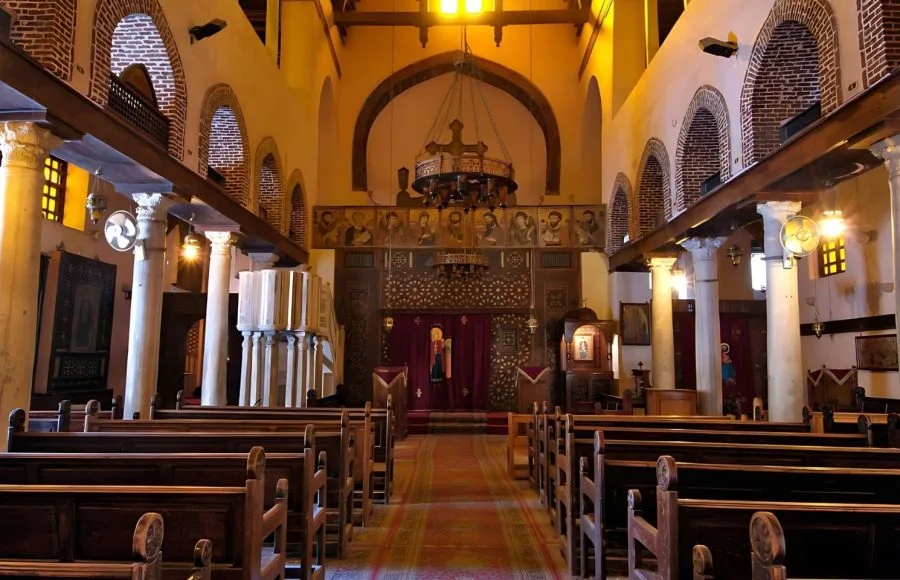 Interior of the historic Church of St. Barbara in Coptic Cairo, showing the nave, aisles, and elaborate sanctuary screen.
