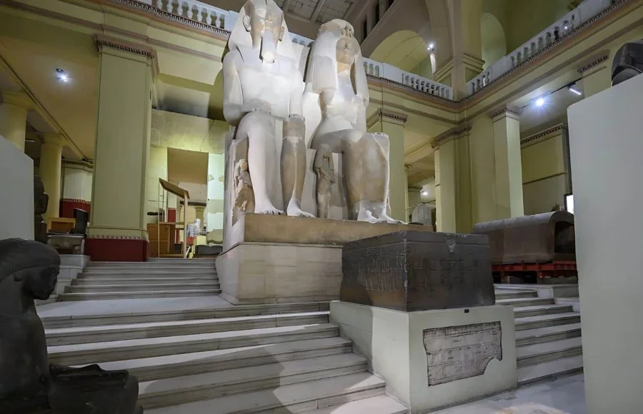 A monumental, seated Colossal Statue of Pharoah Amenhotep III and Queen Tiye at the Egyptian Museum, Cairo, made of white quartzite and displayed at the top of a grand staircase.