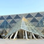 The modern triangular glass entrance of the Grand Egyptian Museum (GEM) in Giza.