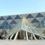 The modern triangular glass entrance of the Grand Egyptian Museum (GEM) in Giza.