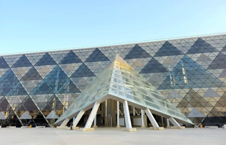 The modern triangular glass entrance of the Grand Egyptian Museum (GEM) in Giza.