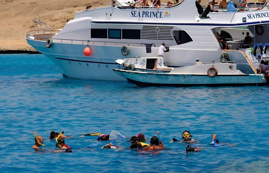 People snorkeling in vibrant blue water, near to Giftun Island.
