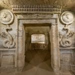 The elaborately carved doorway inside the Catacombs of Kom el-Shoqafa in Alexandria, featuring Hellenistic and pharaonic decorative elements like serpents and relief portraits.