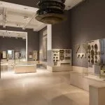 A view of the contemporary and spacious gallery Interior of the Museum of Islamic Art cairo, displaying delicate artifacts, wooden screens, and decorative elements in glass cases.
