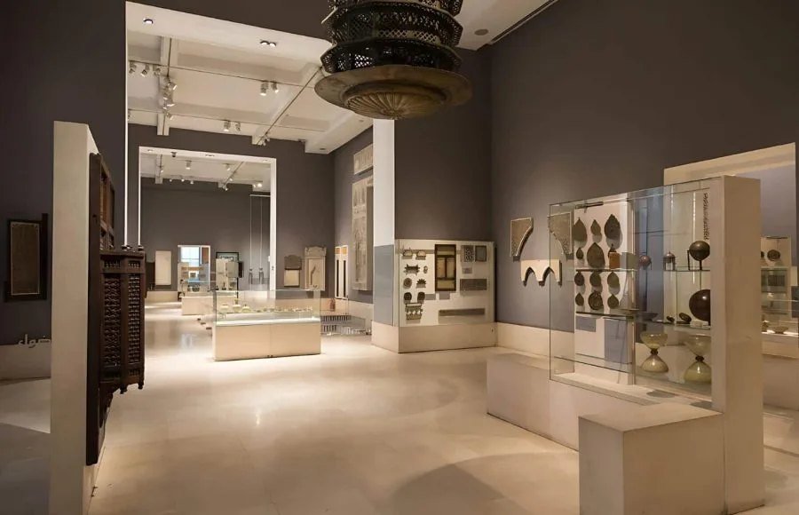 A view of the contemporary and spacious gallery Interior of the Museum of Islamic Art cairo, displaying delicate artifacts, wooden screens, and decorative elements in glass cases.