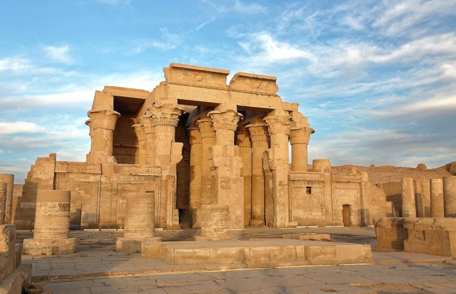 a stone building with pillars with Temple of Kom Ombo in the background