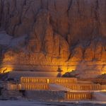 The illuminated facade of the multi-terraced Queen Temple of Hatshepsut, built into the sheer cliffs of Deir el-Bahari on the West Bank of Luxor, showcasing its grandeur at night.