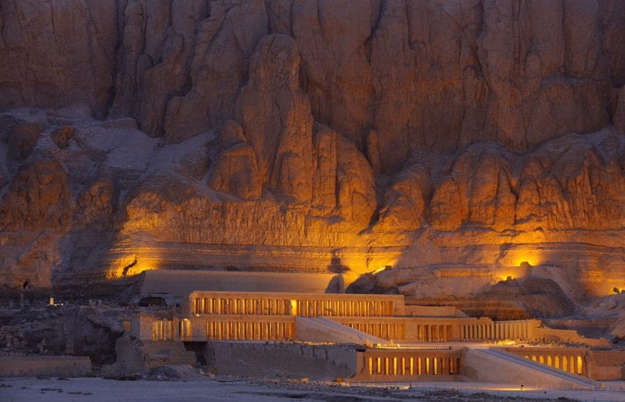 The illuminated facade of the multi-terraced Queen Temple of Hatshepsut, built into the sheer cliffs of Deir el-Bahari on the West Bank of Luxor, showcasing its grandeur at night.