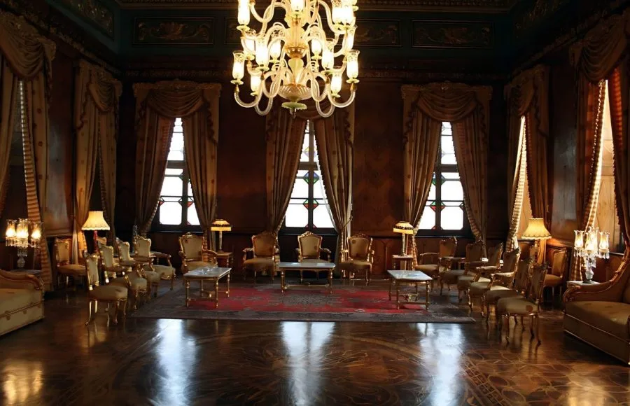The richly decorated Reception Room Mohamed Ali Palace in Egypt, featuring a large chandelier, gilded furniture, marble floor, and heavy velvet curtains.
