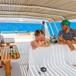 People relaxing on the deck of a boat with clear blue water in Hurghada, some preparing for or returning from snorkeling.