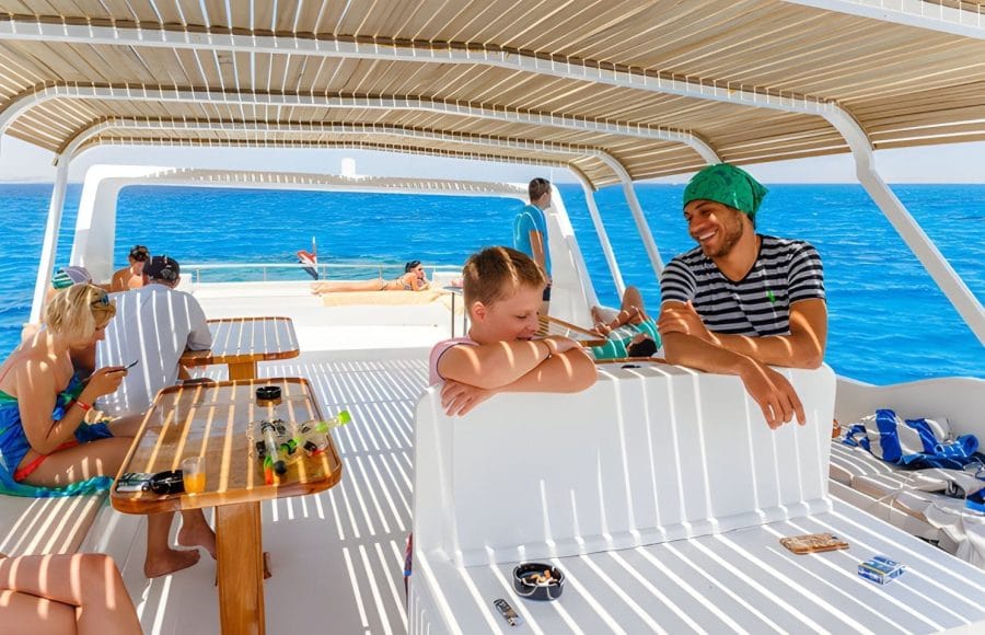 People relaxing on the deck of a boat with clear blue water in Hurghada, some preparing for or returning from snorkeling.