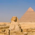 Close-up view of the Great Sphinx of Giza with the Pyramid of Khafre in the background.