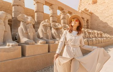 Woman tourist exploring the Avenue of Sphinxes in Karnak Temple Luxor Egypt ancient architecture