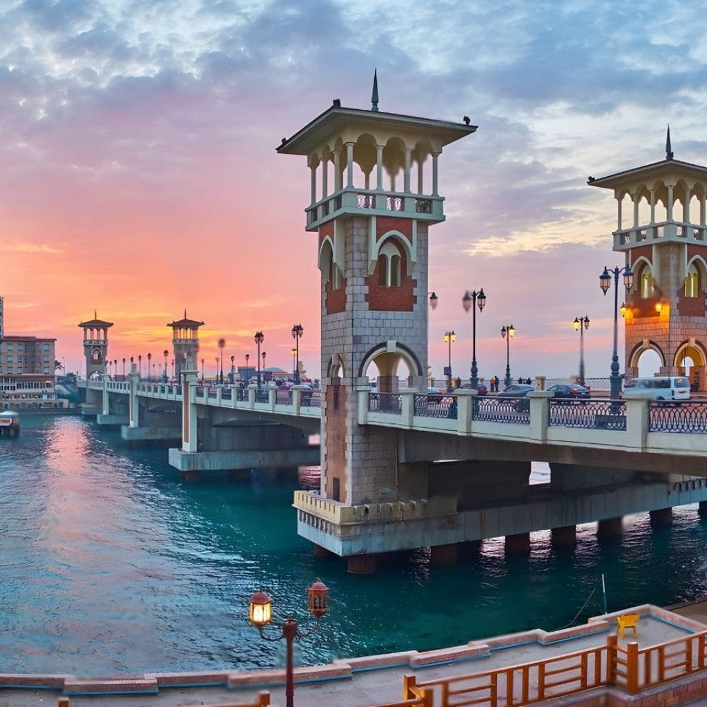 The Stanley Bridge Alexandrina Trip At Sunset, Showing The Ornate Towers And Structure Arching Over The Turquoise Sea, Connecting The Coastline Of Alexandria.