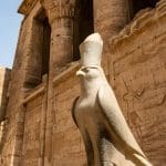 Statue of the falcon god Horus guarding the exterior pylon of the well-preserved Temple of Edfu, along the Nile River.