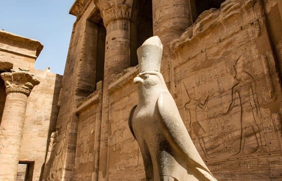 Statue of the falcon god Horus guarding the exterior pylon of the well-preserved Temple of Edfu, along the Nile River.