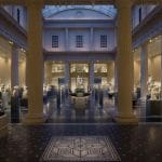 The grand hall The Greco-Roman Museum in Alexandria, featuring tall columns, a mosaic floor, and classical statues displayed throughout the spacious interior.