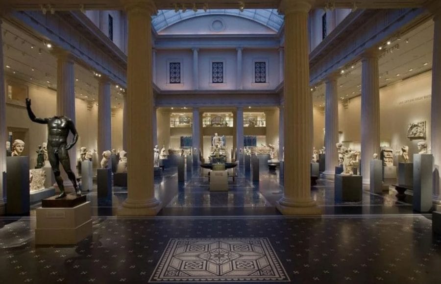 The grand hall The Greco-Roman Museum in Alexandria, featuring tall columns, a mosaic floor, and classical statues displayed throughout the spacious interior.