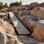 Tourists stand around the Unfinished Obelisk in Aswan, a massive granite monument still attached to the bedrock of the ancient quarry