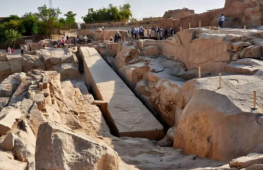 Tourists stand around the Unfinished Obelisk in Aswan, a massive granite monument still attached to the bedrock of the ancient quarry
