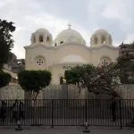 The exterior facade of the Virgin Mary Church Zaitoun in Cairo with multiple domes and a cross.