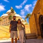 A couple of tourists smiling at the camera in front of the Mosque of Muhammad Ali Pasha at the Citadel of Cairo.