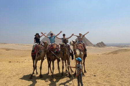 Tourists Enjoying A Camel Ride Adventure With A Guide Near The Great Pyramids Of Giza Egypt