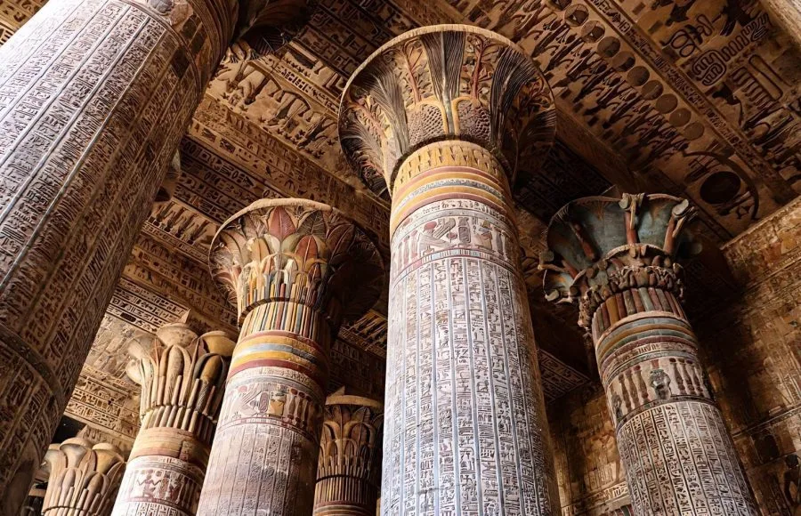 An upward view of the Colorful Columns of the Ancient Khnum Temple in Esna, showing the magnificent original colors and detailed hieroglyphic reliefs on the columns and ceiling.