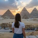 Tourist watching the sunset over the three Great Pyramids of Giza Cairo Egypt landmark view