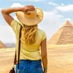 Female tourist wearing a hat gazing at the Great Pyramids of Giza Egypt desert landmark