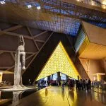 Interior atrium of the Grand Egyptian Museum (GEM) with a colossal statue and modern architectural design.