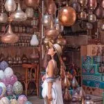 Girl tourist admiring the colorful metal lamps and handcrafted goods in the bustling Khan El Khalili market in Cairo.
