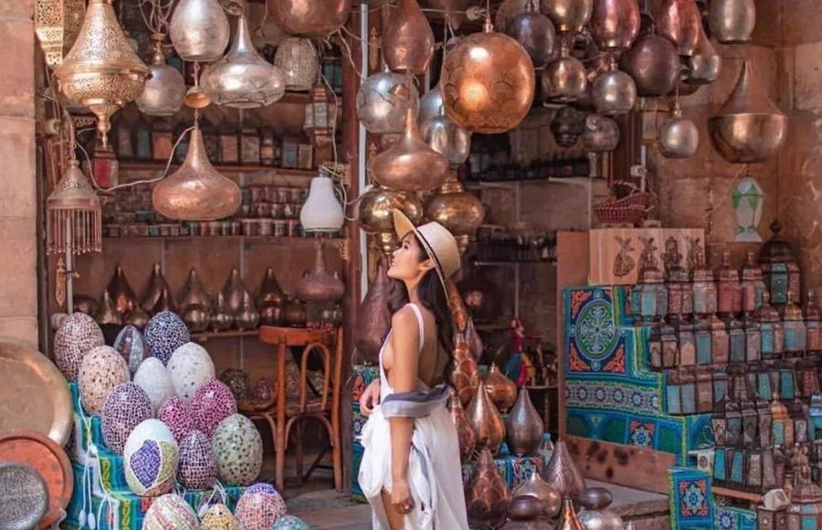 Girl tourist admiring the colorful metal lamps and handcrafted goods in the bustling Khan El Khalili market in Cairo.