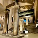 Interior view of the Grand Egyptian Museum (GEM) featuring massive stone lotus columns and ancient monuments in a modern hall.