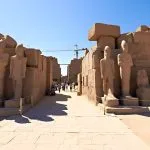 The entrance to Karnak Temple, with a row of human-headed sphinxes on either side of the walkway.