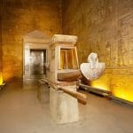 A view of the beautifully preserved ritual barque and shrine, including a white falcon statue, inside The Sanctuary Inside Temple of Edfu Egypt, illuminated by warm golden light.