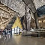 Tourists viewing the colossal statue in the stunning, sunlit atrium of the new Grand Egyptian Museum in Giza.