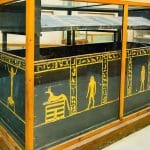 A black granite Valley Of The Kings granet Coffin displayed in a museum, intricately decorated with golden yellow hieroglyphs and scenes, originally from the tombs in the Valley of the Kings.
