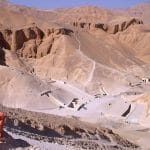 A tourist looking at the Valley of the Kings desert landscape in Luxor, showing tomb entrances.
