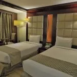 A clean and comfortable twin cabin on the Blue Shadow i Nile Cruise, featuring two single beds, modern decor, and a large window offering panoramic views of the Nile.